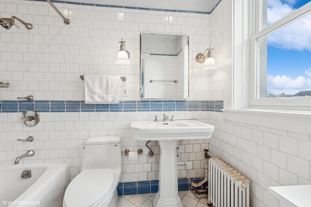 bathroom with plenty of natural light, toilet, tile walls, and radiator