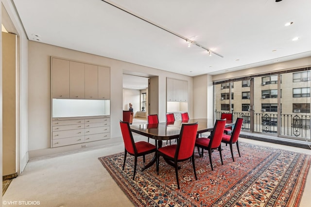 dining space with light colored carpet and track lighting