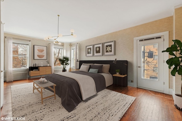 bedroom with access to outside, radiator, a chandelier, and wood-type flooring