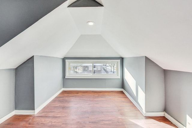 additional living space with hardwood / wood-style flooring and lofted ceiling