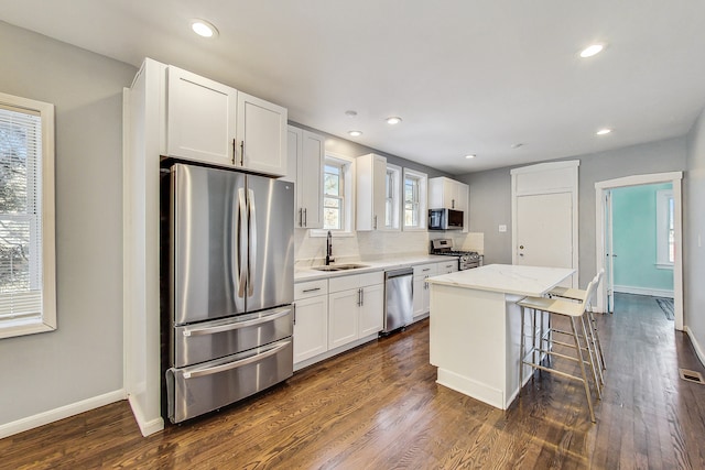 kitchen with appliances with stainless steel finishes, sink, dark hardwood / wood-style flooring, and a kitchen island