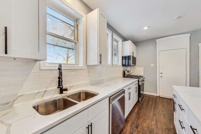 kitchen featuring white cabinets, appliances with stainless steel finishes, sink, and light stone countertops