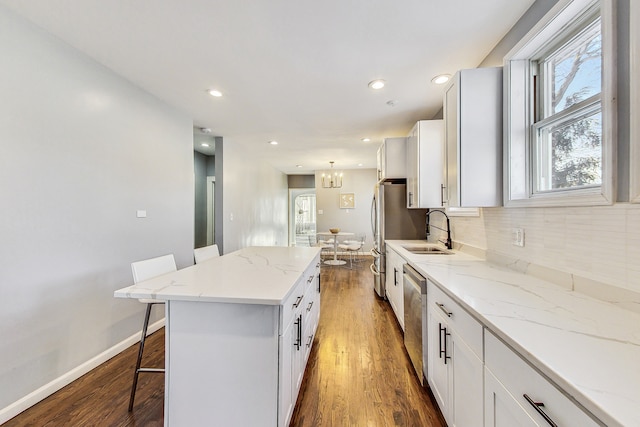 kitchen featuring hardwood / wood-style floors, dishwasher, a center island, backsplash, and a breakfast bar area