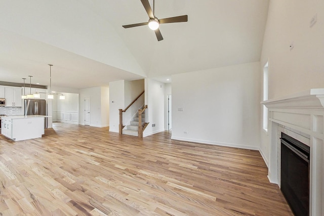 unfurnished living room featuring ceiling fan, light hardwood / wood-style flooring, and high vaulted ceiling