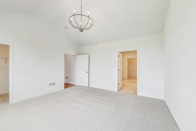 unfurnished bedroom featuring a walk in closet, a chandelier, light carpet, and a closet