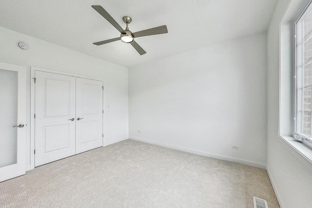 unfurnished bedroom with ceiling fan, light carpet, and a closet