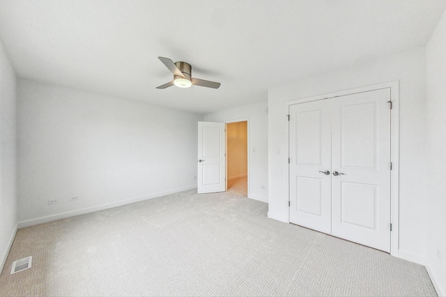 unfurnished bedroom featuring ceiling fan, light colored carpet, and a closet