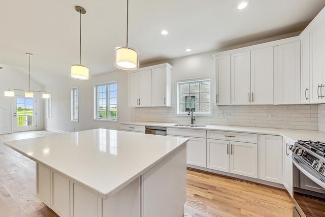 kitchen featuring decorative backsplash, light hardwood / wood-style flooring, appliances with stainless steel finishes, a center island, and sink