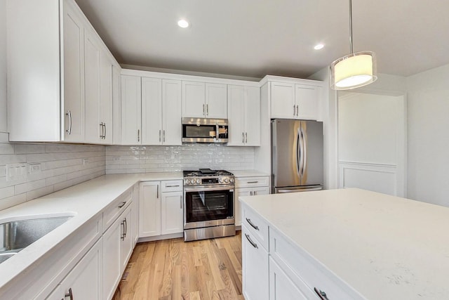 kitchen featuring tasteful backsplash, stainless steel appliances, light hardwood / wood-style flooring, and white cabinetry