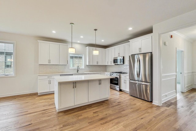 kitchen with light hardwood / wood-style flooring, stainless steel appliances, a kitchen island, and backsplash