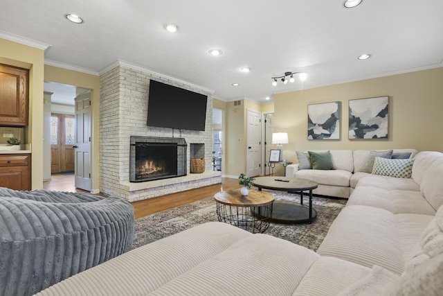 living room with hardwood / wood-style flooring, ornamental molding, and a brick fireplace