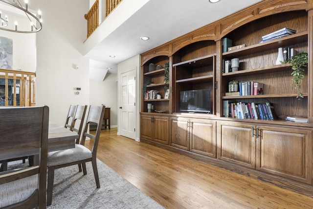 home office featuring a high ceiling, a chandelier, and light hardwood / wood-style flooring