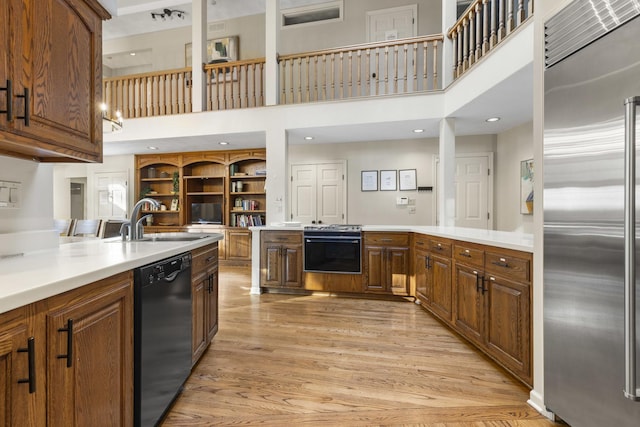 kitchen featuring sink, dishwasher, built in fridge, light hardwood / wood-style floors, and kitchen peninsula