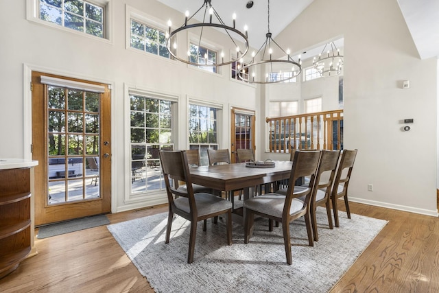 dining area featuring an inviting chandelier, plenty of natural light, high vaulted ceiling, and light hardwood / wood-style flooring