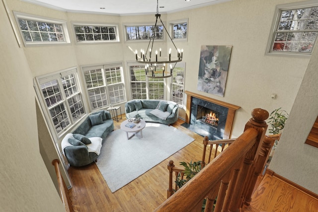 living room featuring a premium fireplace, ornamental molding, hardwood / wood-style floors, and a notable chandelier