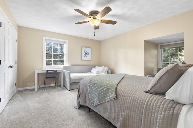 bedroom featuring multiple windows, light carpet, and ceiling fan