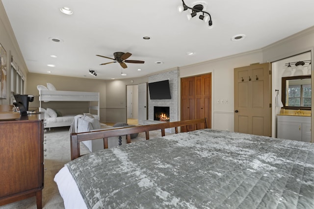 bedroom featuring a brick fireplace, crown molding, and dark colored carpet