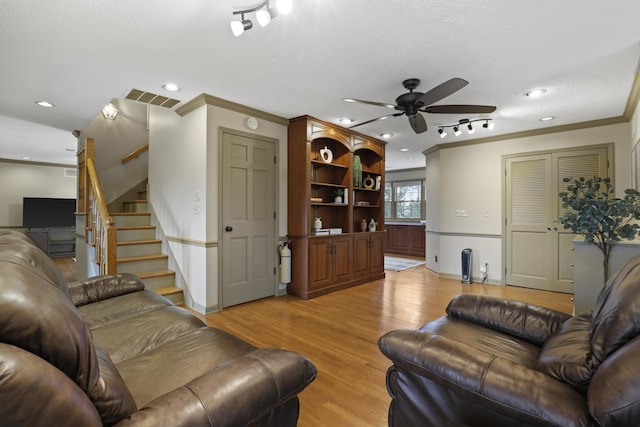 living room featuring ceiling fan, ornamental molding, light hardwood / wood-style flooring, and a textured ceiling