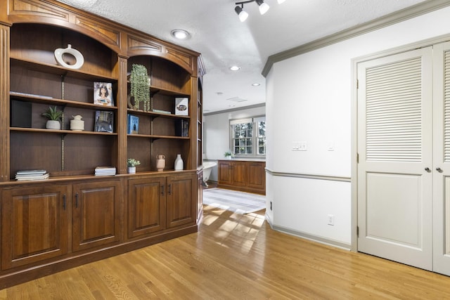 bar with crown molding, a textured ceiling, and light wood-type flooring