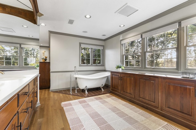 bathroom with hardwood / wood-style flooring, ornamental molding, vanity, and a bathtub