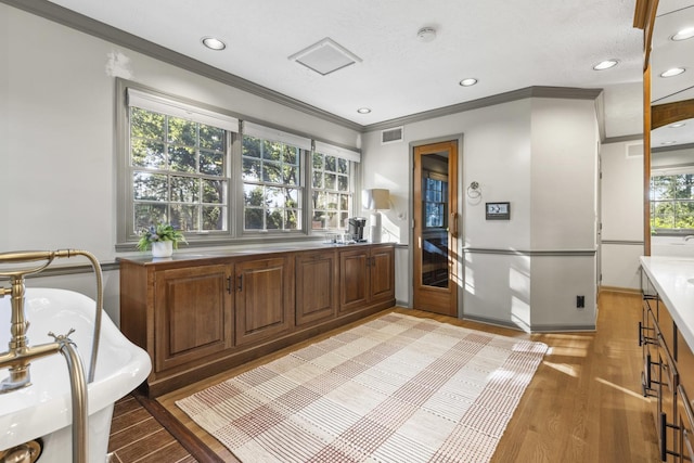 bathroom featuring ornamental molding, wood-type flooring, a bathing tub, and vanity