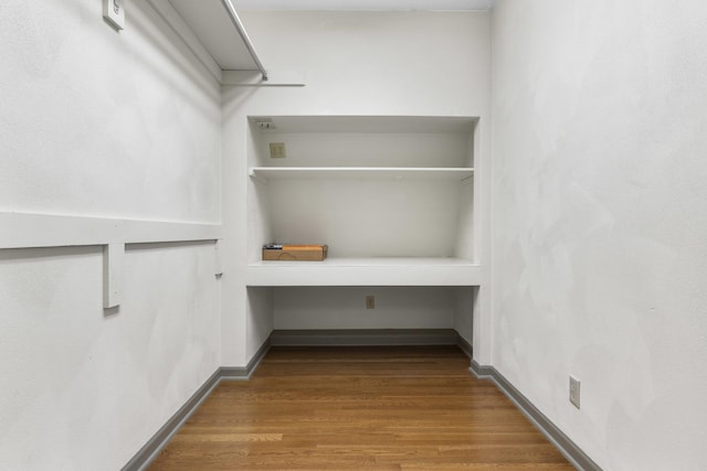 spacious closet with hardwood / wood-style flooring and built in desk