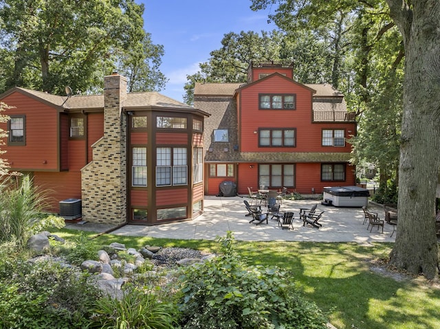 rear view of property with a hot tub and a patio