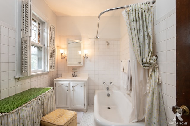 bathroom featuring shower / bath combo, tile patterned flooring, vanity, and tile walls