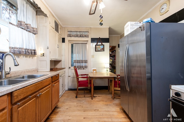 kitchen featuring sink, crown molding, light wood-type flooring, stainless steel fridge, and ceiling fan