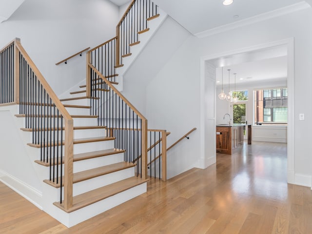 staircase with sink, a chandelier, and hardwood / wood-style floors