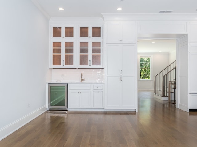 bar with white cabinets, ornamental molding, beverage cooler, and wood-type flooring