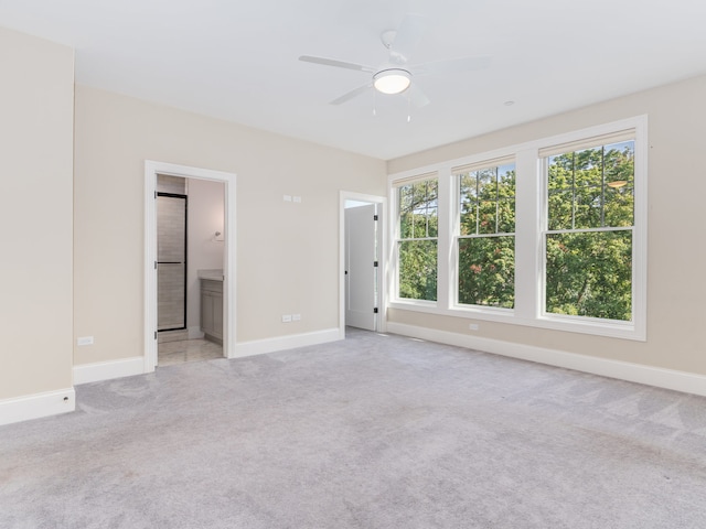 interior space with ensuite bathroom, light carpet, and ceiling fan