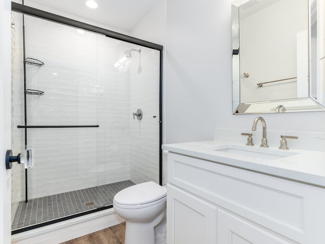 bathroom with hardwood / wood-style floors, toilet, vanity, and an enclosed shower