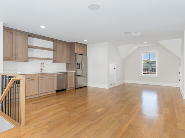 kitchen featuring appliances with stainless steel finishes, sink, light wood-type flooring, and lofted ceiling