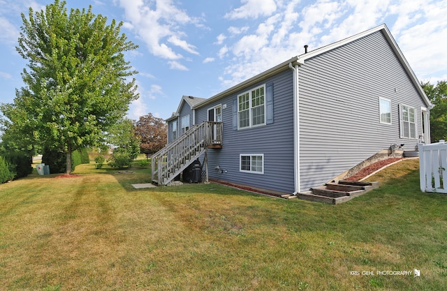 view of side of home with a yard, central AC, and a wooden deck