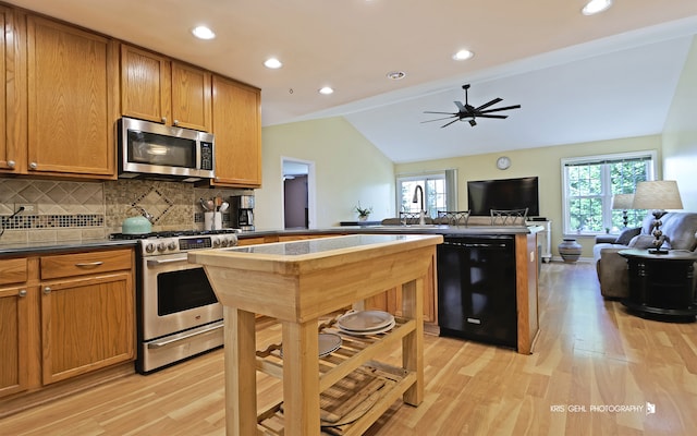 kitchen featuring tasteful backsplash, kitchen peninsula, stainless steel appliances, light wood-type flooring, and lofted ceiling