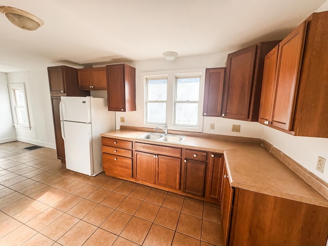 kitchen with white refrigerator, light tile patterned flooring, and sink