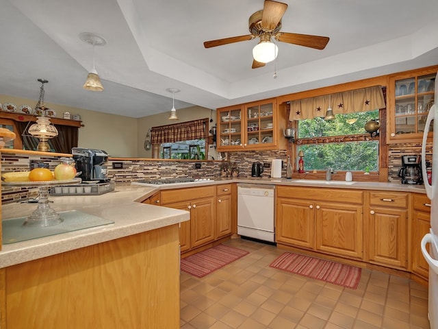 kitchen with hanging light fixtures, white dishwasher, sink, light tile patterned floors, and decorative backsplash