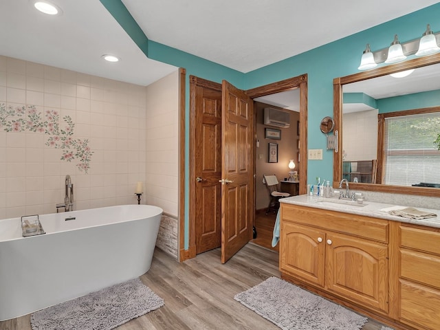 bathroom with a bath, tile walls, wood-type flooring, vanity, and a wall mounted air conditioner