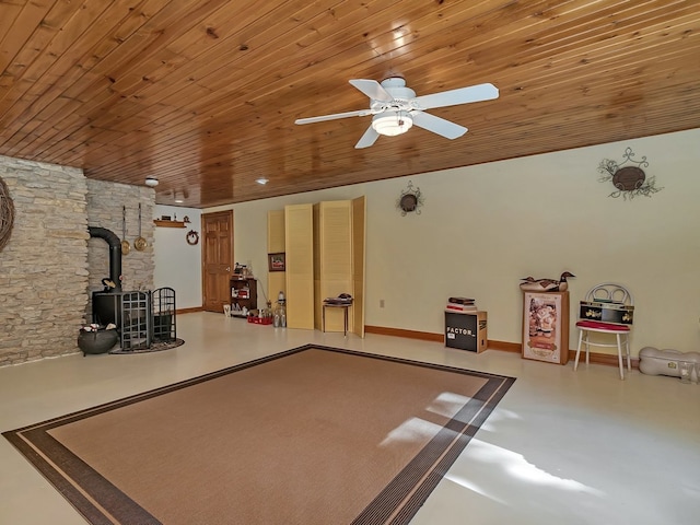 playroom featuring ceiling fan, a wood stove, and wood ceiling