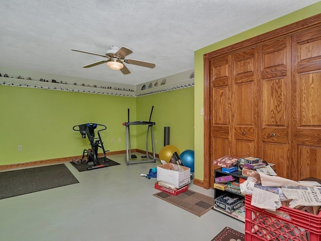 exercise room featuring ceiling fan, concrete floors, and a textured ceiling