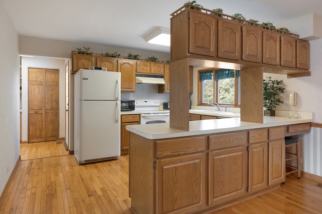 kitchen with kitchen peninsula, white appliances, light hardwood / wood-style floors, and sink