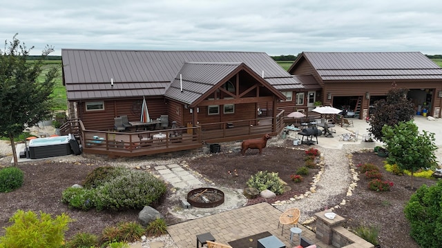 back of property featuring a wooden deck, a hot tub, a patio area, a fire pit, and outdoor dining space