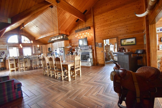 dining area with a stone fireplace, wood walls, beamed ceiling, high vaulted ceiling, and wood ceiling