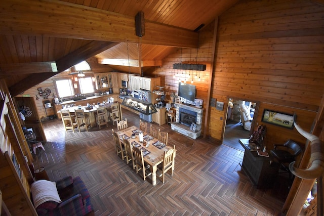living room with wood walls, wood ceiling, a ceiling fan, and lofted ceiling with beams