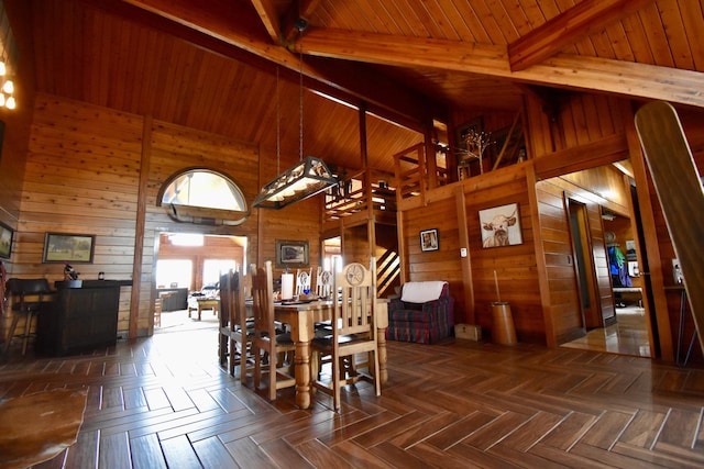 dining space with high vaulted ceiling, wooden walls, beamed ceiling, and stairway