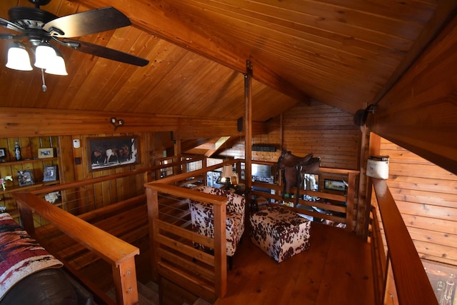 living area featuring wooden walls, lofted ceiling with beams, and wood ceiling