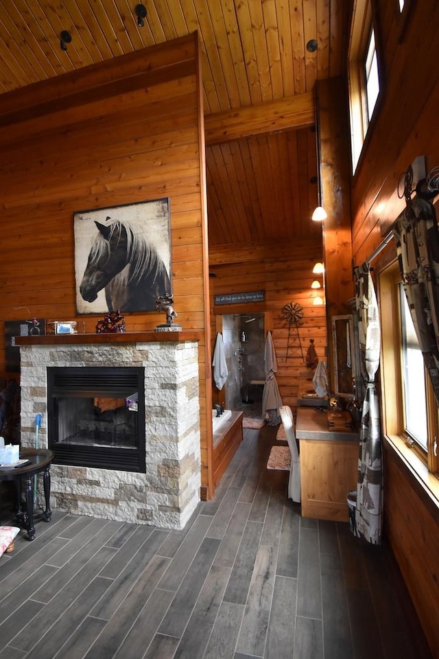 living room with wood ceiling, wooden walls, beamed ceiling, and a stone fireplace