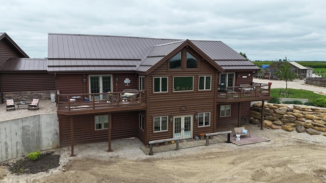 back of house featuring french doors, metal roof, faux log siding, and a wooden deck