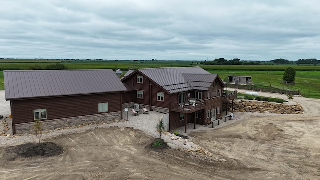 exterior space with a rural view, metal roof, stone siding, and a wooden deck
